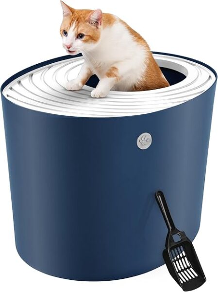 An orange and white cat is climbing out of the top of a navy blue IRIS Top Entry Cat Litter Box. The box has a white, grooved lid designed to catch litter, and a black scoop rests against the side.